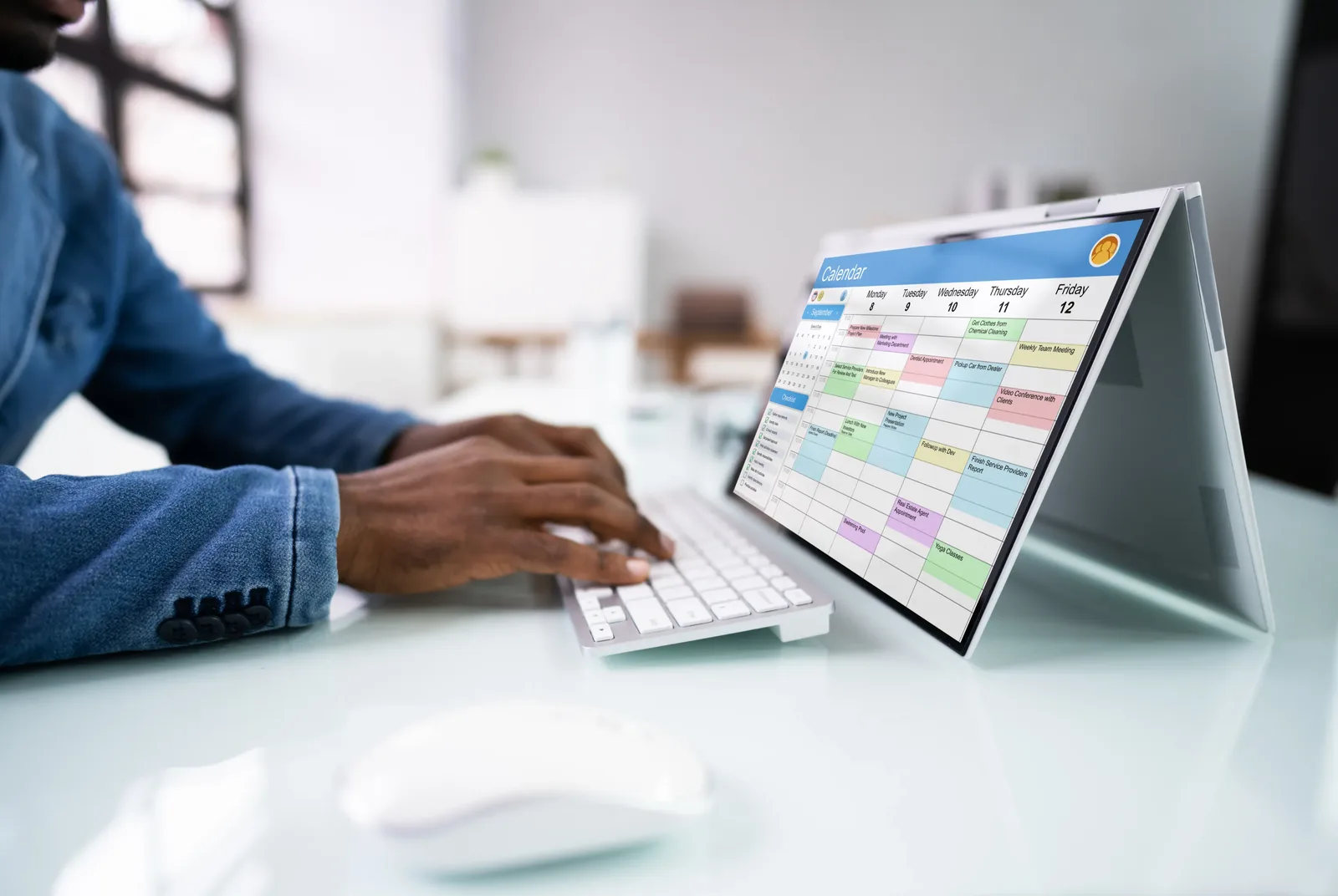 A person at a desk arranging appointments in a calendar application on a laptop.